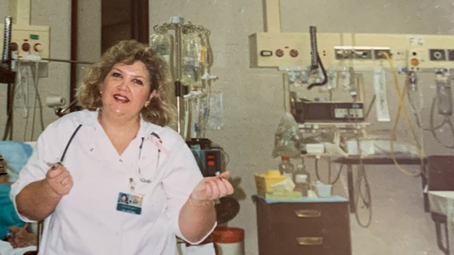 A nurse smiling in a hospital room.