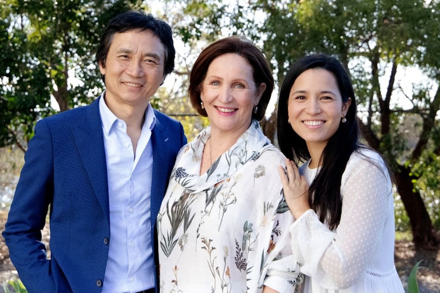 A portrait of a husband and wife and adult daughter in outdoors setting