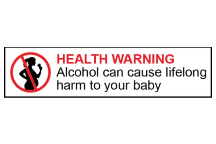 A label shows the silhouette of a pregnant woman drinking with the words HEALTH WARNING: Alcohol can cause lifelong harm to baby