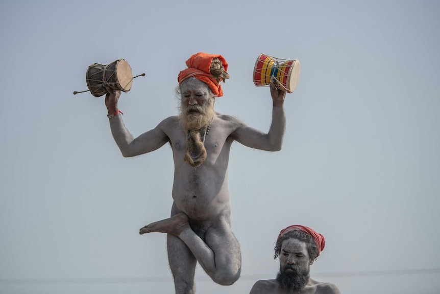 A naked Hindu holy man poses on one leg