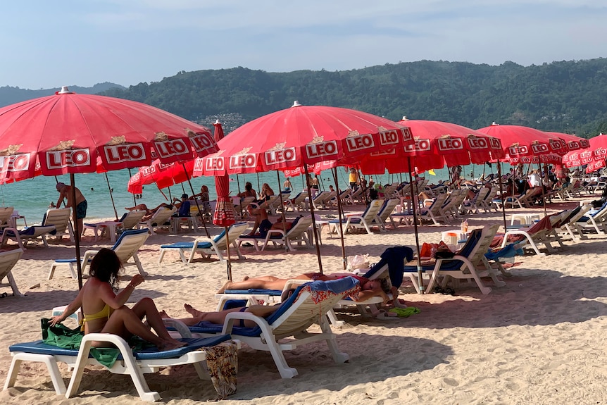 Tourist on a beach, on sunbeds under umbrellas, in swimwear. 