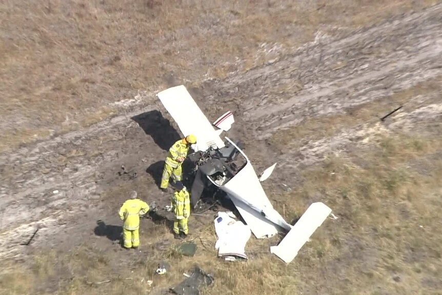 Firefighters inspect the wreckage of a light aircraft in a field.