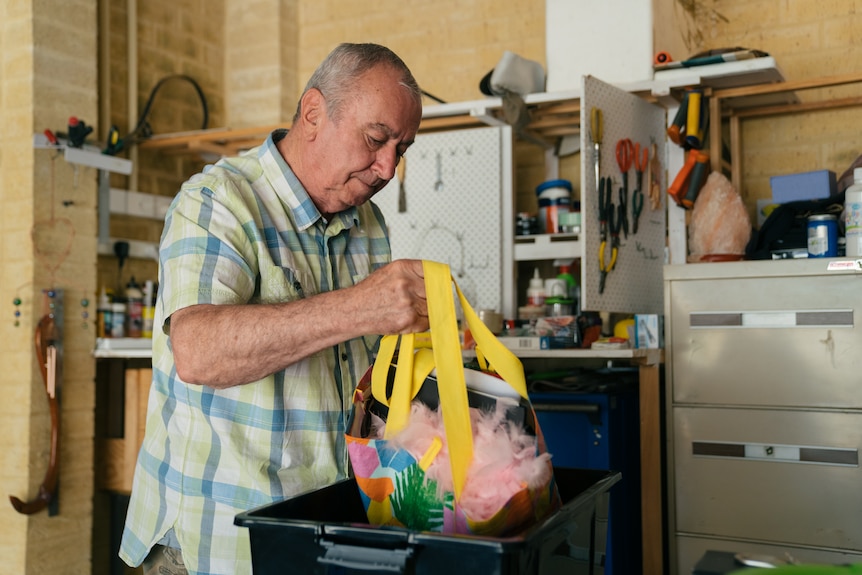 A man is placing a bag in a plastic box.