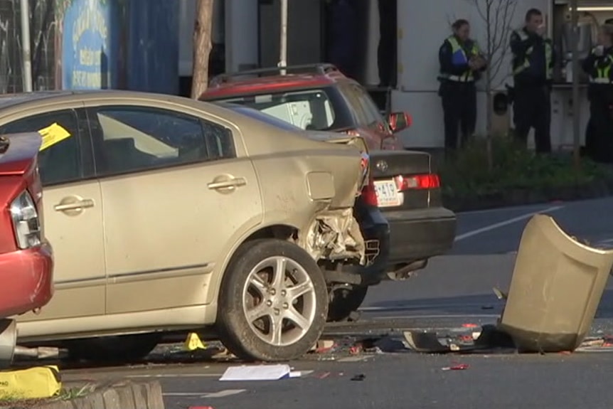 A car parked on a residential street with its bumper bar smashed and lying on the ground, alongside debris and glass.