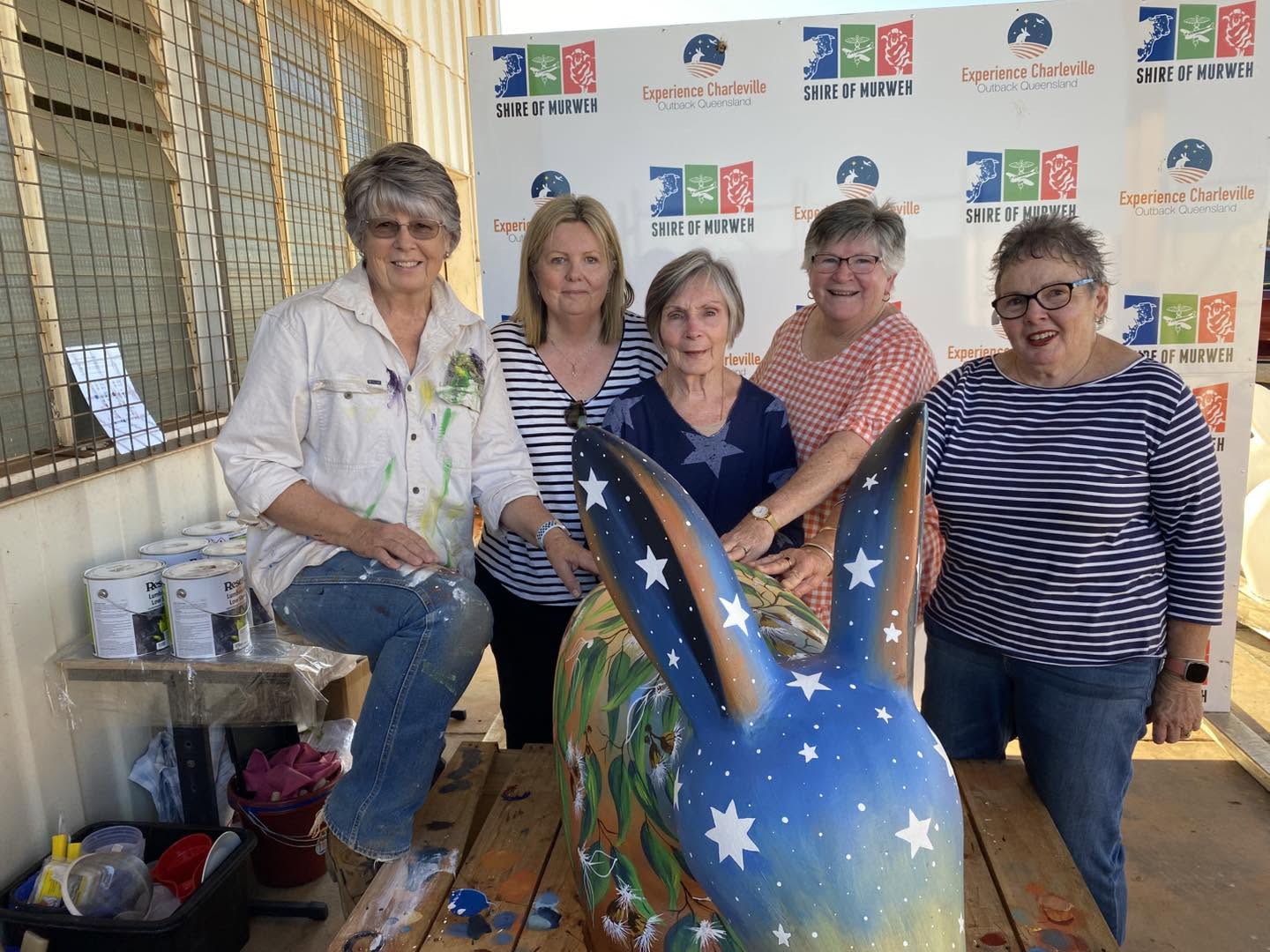 five women stand behind a painted cement bilby