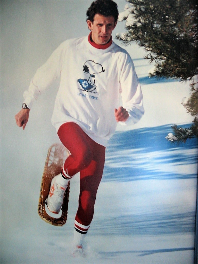 Action shot of a man in activewear concentrating on running in snowshoes through snow.