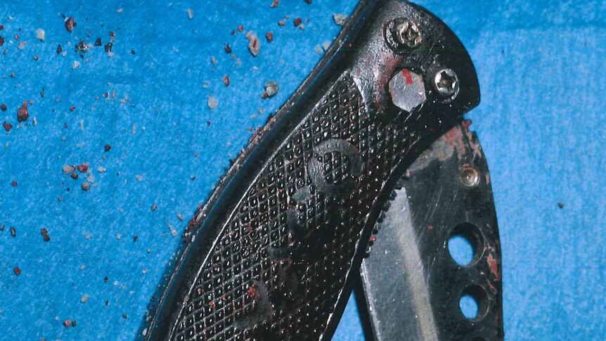A black switchblade knife partially opened on a blue background.