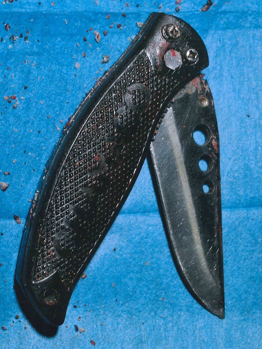 A black switchblade knife partially opened on a blue background.