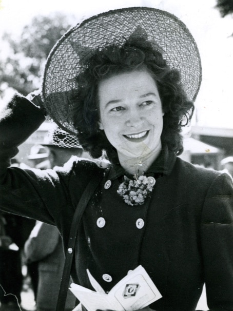 A black and white image of a young woman in the 1960s. She is wearing a hat and holding a pamphlet