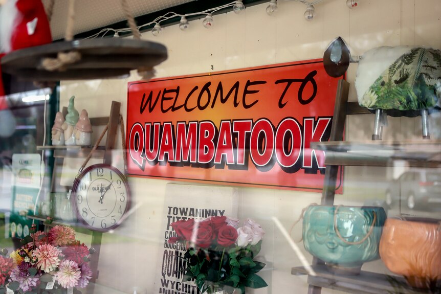 An orange sign in a shop window that reads Welcome to Quambatook