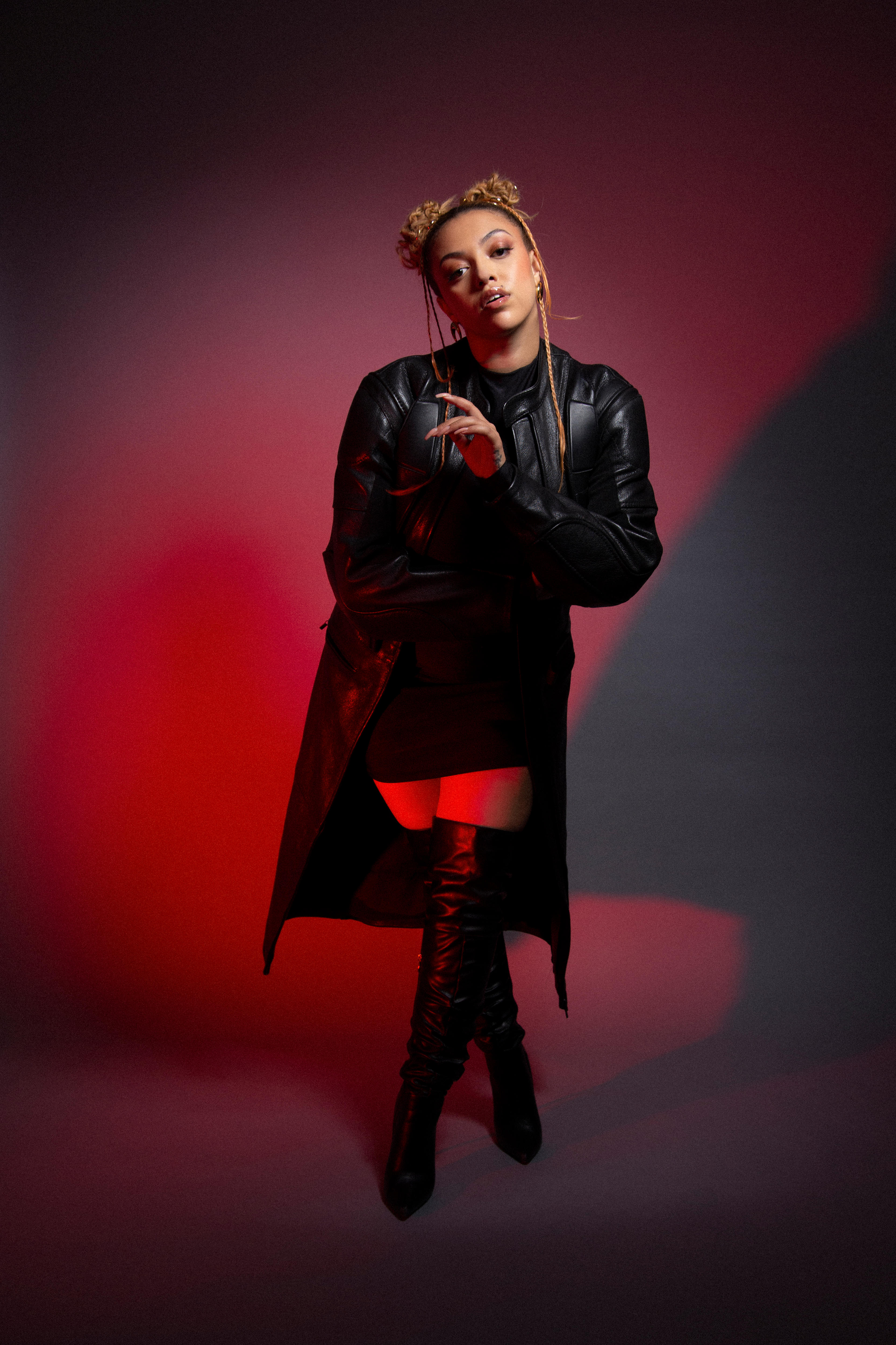 Mahalia is in a black leather coat and her hair back with a red gradient background