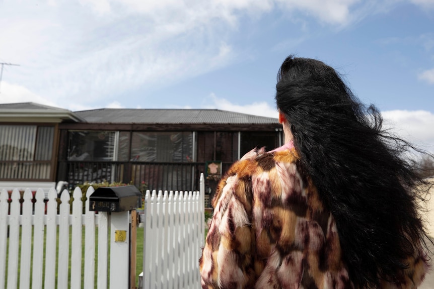 A woman with black hair walks up a driveway