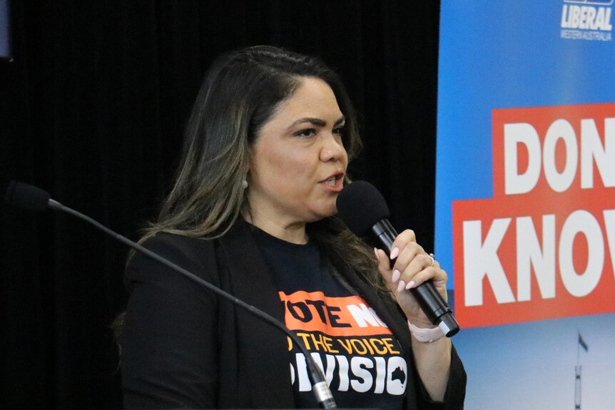 A woman wearing black speaks at a lectern indoors. Behind her is a Liberal party-branded banner that reads 'DON'T KNOW'.