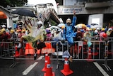 Pro-democracy protesters, dressed in colourful raincoats and with umbrellas, try and cross a barrier in Bangkok.