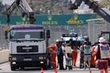Cranes and trucks help move a Formula One car from the track during a practice session.
