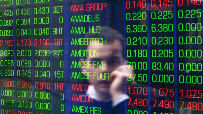 An office worker talks on his phone as he looks the stock board at the Australian Securities Exchange