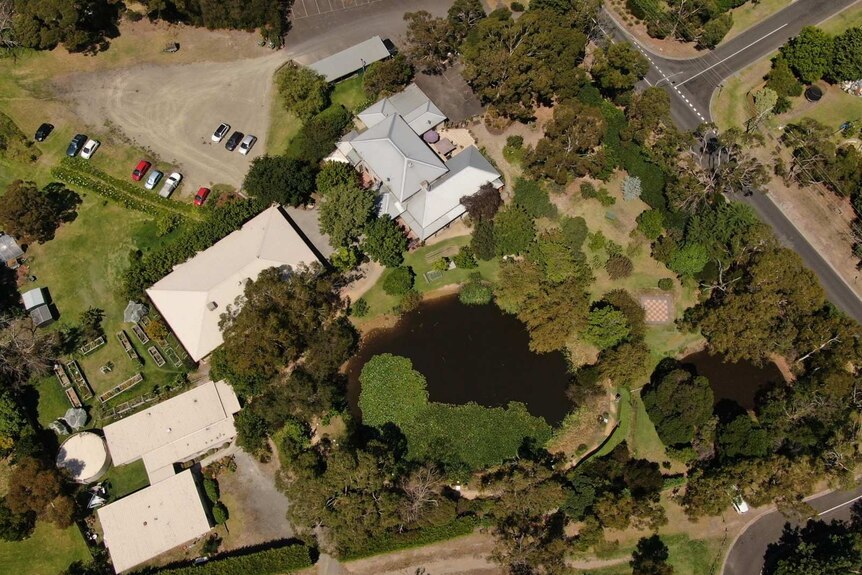 An aerial image of the The Ashram at Mt Eliza, showing several buildings, a gravel car park and two lakes and expansive gardens.