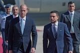 Prince William and Crown Prince Hussein walk side by side, both in blue suits