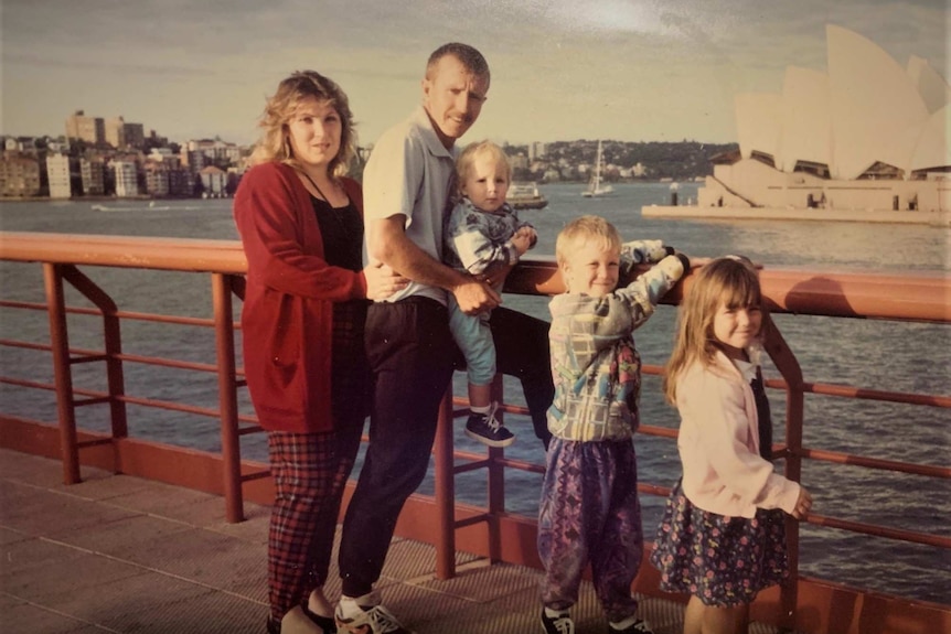 Two parents and three kids with the Sydney Opera House in the background across the harbour.