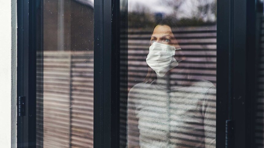 Woman wearing mask looking out window