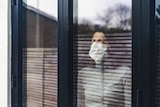 Woman wearing mask looking out window