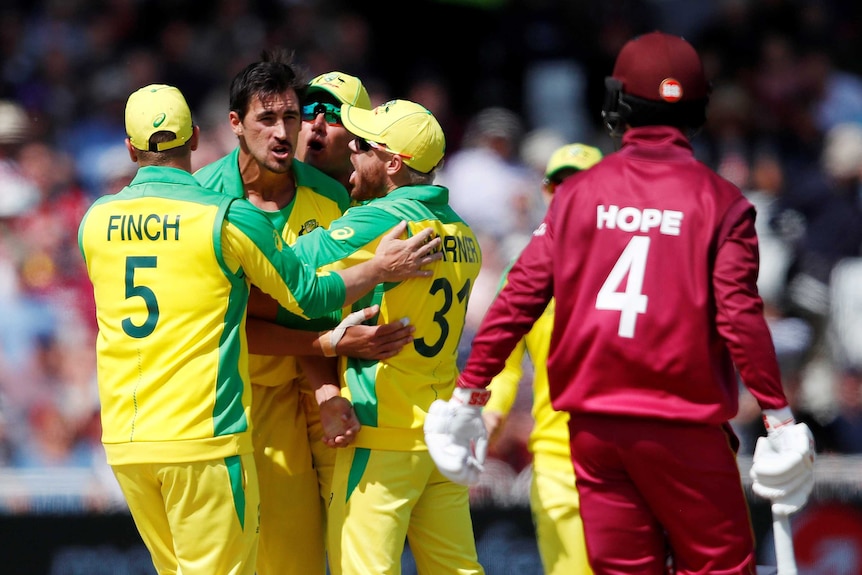 Mitchell Starc is embraced by teammates with Hope in the foreground.