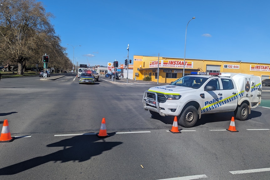 Police car and witches hats block a major road.