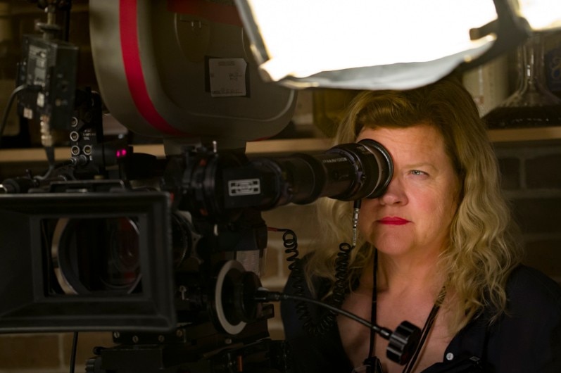 A woman looking through a camera on a film set.