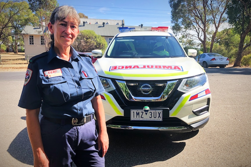 A woman in uniform in front of her emergency vehicle.