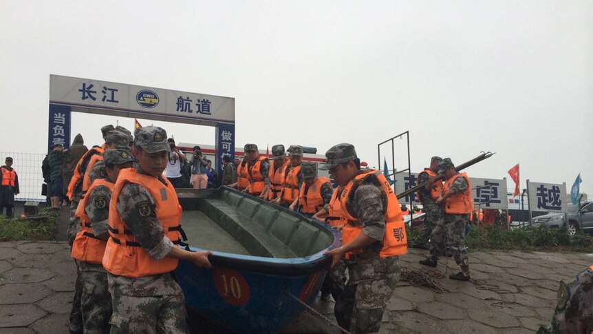 Rescue workers carry boats onto the Yangtze river to search for more than 400 passengers from a capsized ferry