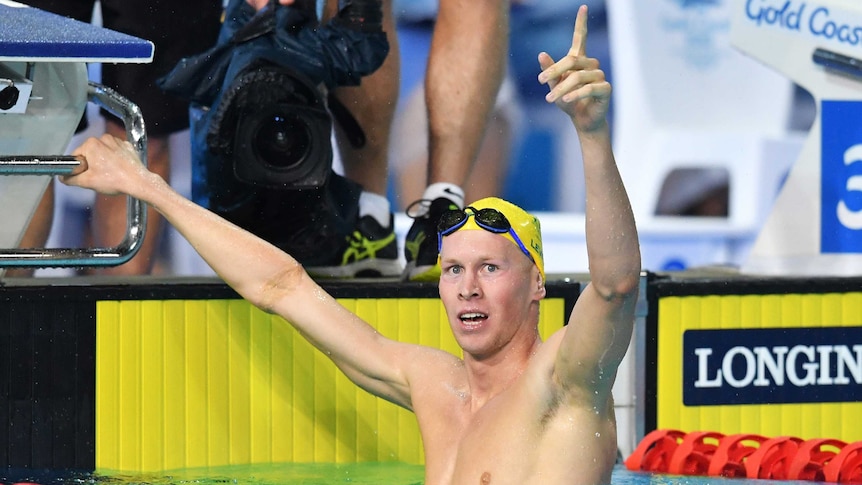 Australian swimmer Clyde Lewis lifts his arm in the air in triumph after winning gold.