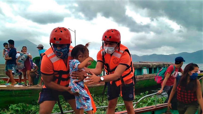 Members of the Philippine Coast Guard carry a child as they are evacuate her to safer ground.