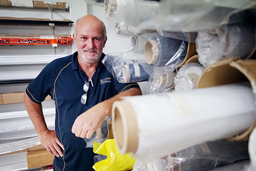 Adrian Moscheni is standing in the warehouse at Straitline Blinds and smiling at the camera.