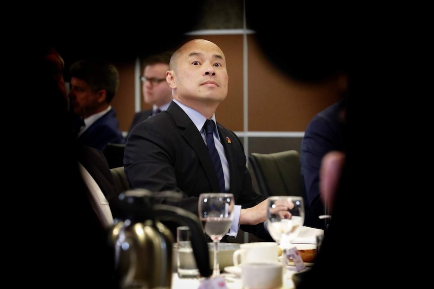 Wang Xining dans une salle à manger, encadrée par d'autres personnes.