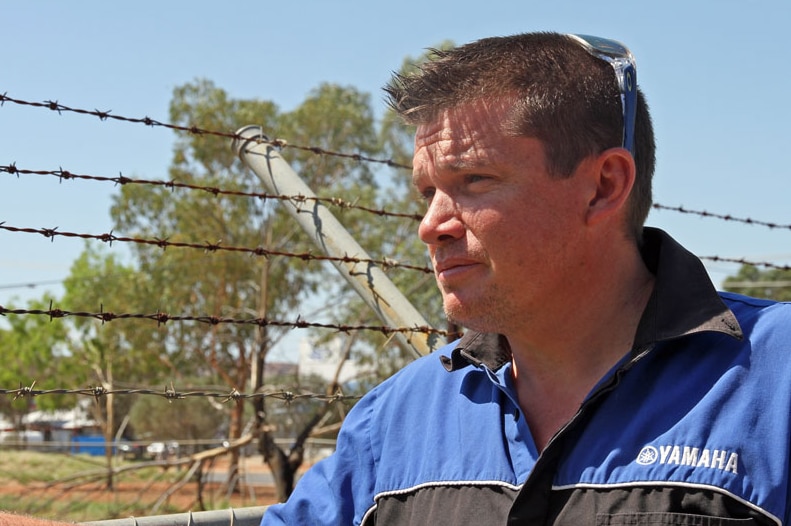 Small business owner Garth Thompson stands next to a barbed wire fence on the perimeter of his complex