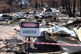 Sign warning of asbestos outside a burned out home in Yarloop