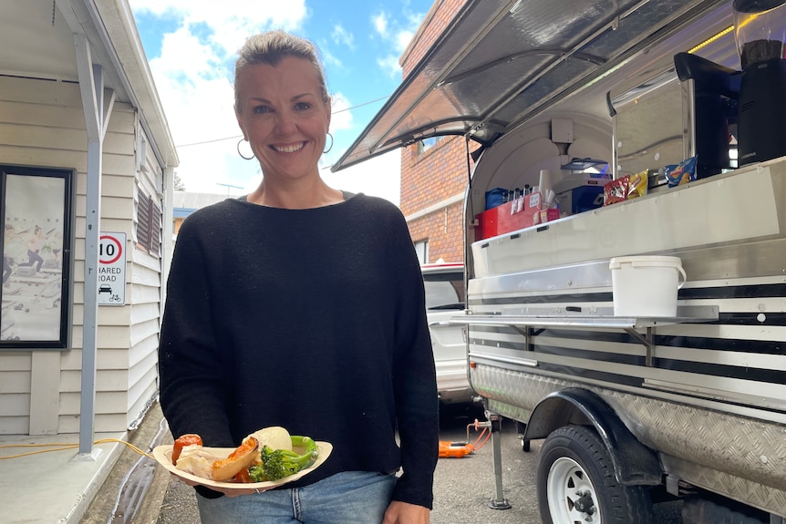 a woman stands smiling near a food truck