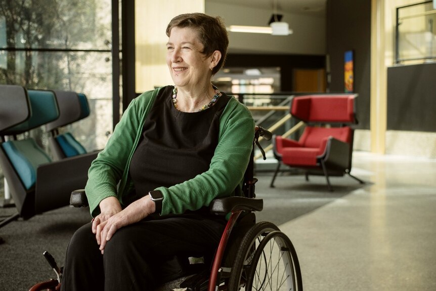 A middle aged woman in a wheelchair looks into the distance