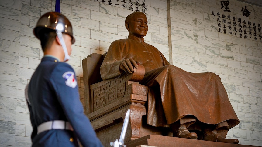 A soldier stands in front of a big bronze statue of Chiang Kai-shek