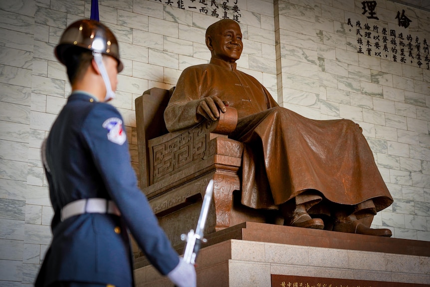 A soldier stands in front of a big bronze statue of Chiang Kai-shek