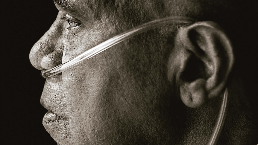 A side-profile photo of Archie Roach, who has a breathing tube in his nose and wrapped around his ear