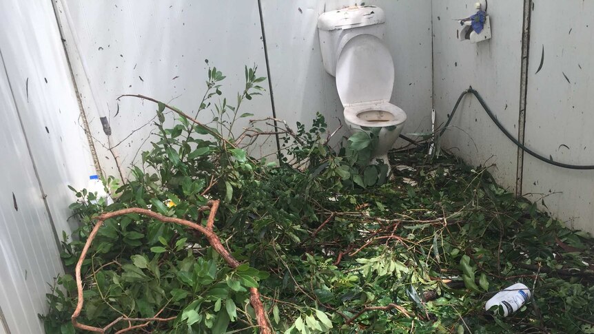 Fallen tree branches and debris from Cyclone Trevor litter a toilet block.