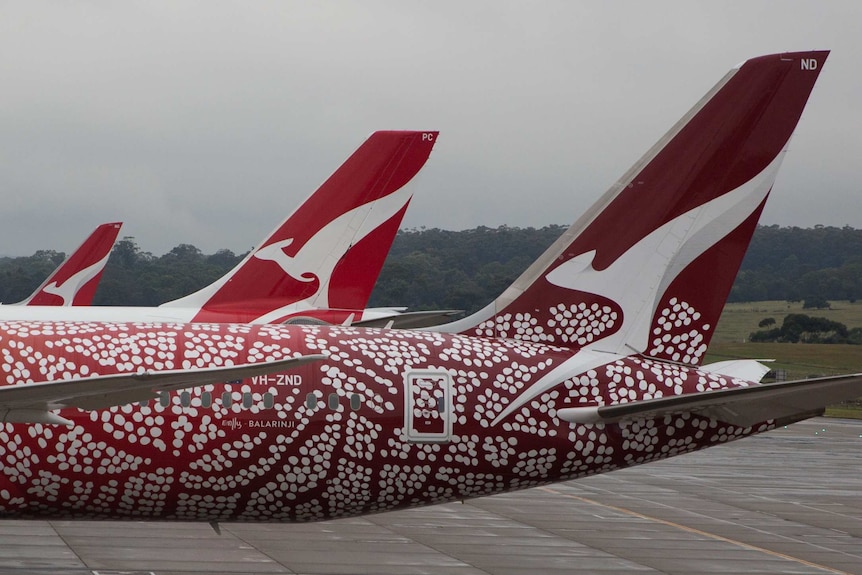 Three Qantas planes on the tarmac at Melbourne Airport on a stormy day