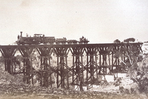 Black and white photo of a train crossing a wooden bridge
