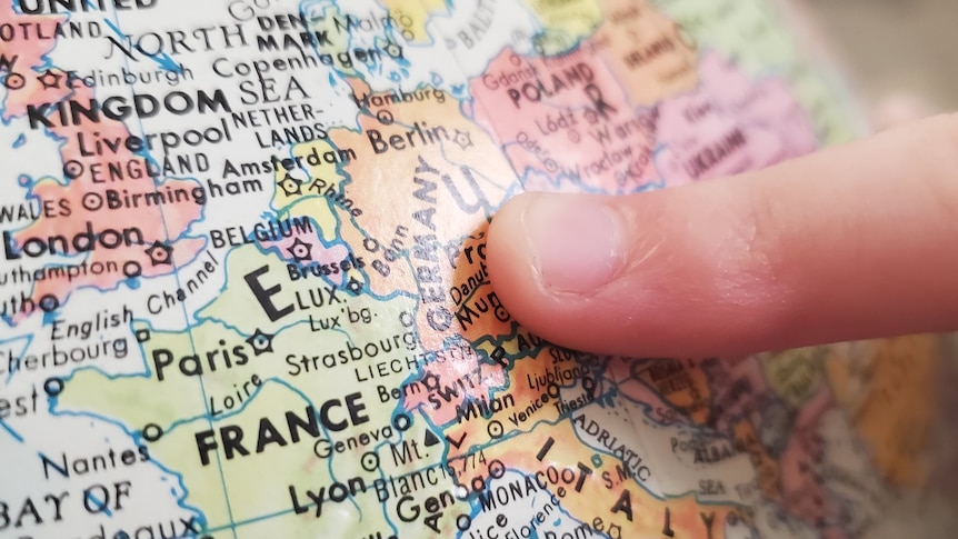 A finger pointing to a map of France, near its borders with Belgium and Germany