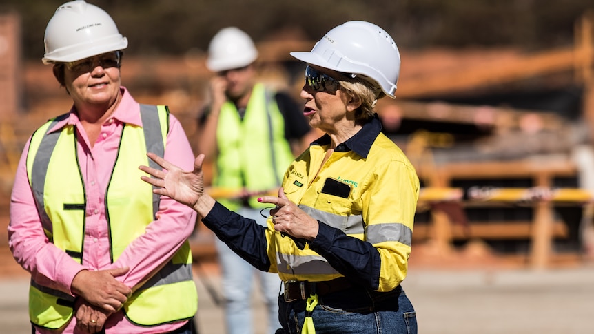 Two women wearing high-vis and hard hats on a construction site.