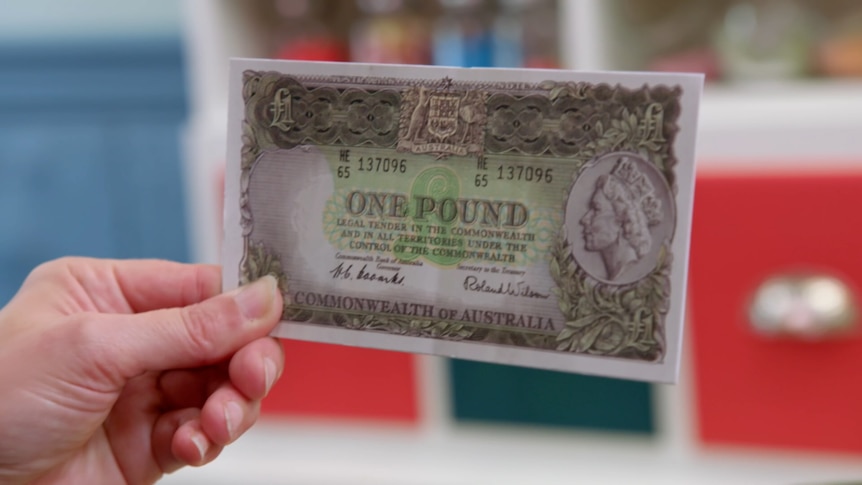 A hand holds a one pound note