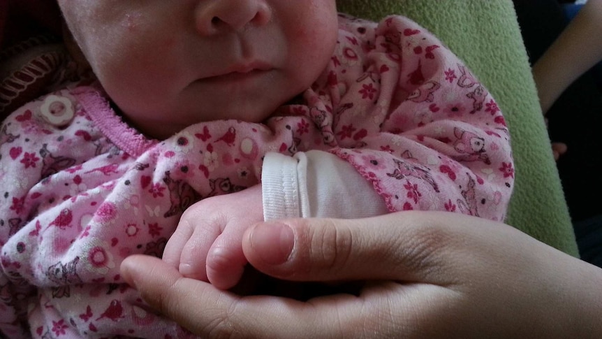 A parent offers a hand to a small baby