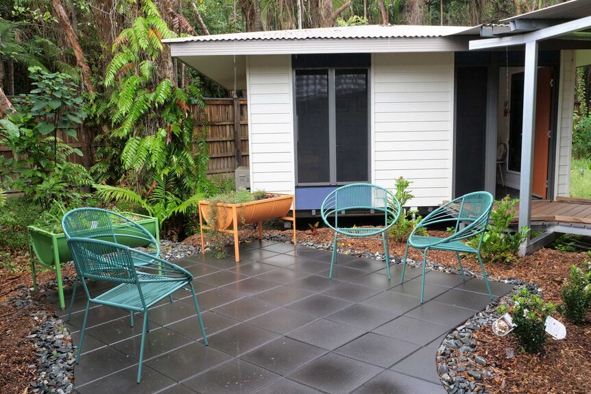 Paved garden with blue chair and colourful planter boxes