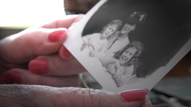 Hands hold old photo of woman and two children